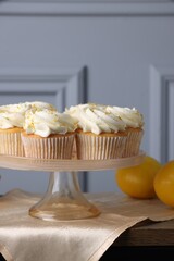 Delicious lemon cupcakes with white cream on table