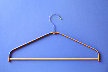 One wooden hanger on blue background, top view