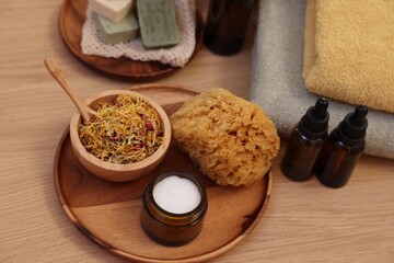 Dry flowers, bottles of essential oils, loofah and jar with cream on wooden table. Spa time