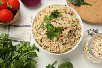 Tasty quinoa porridge with parsley in bowl on white marble table, flat lay