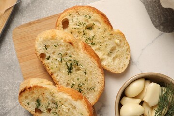 Tasty baguette with garlic and dill on light grey table, top view