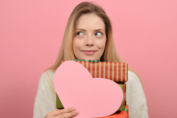 Beautiful young woman with paper heart on color background. Valentine's day celebration