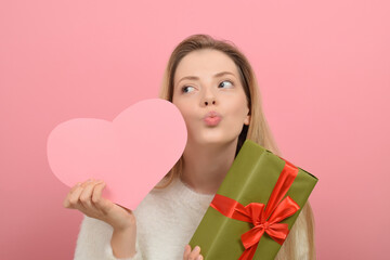 Beautiful young woman with paper heart on color background. Valentine's day celebration