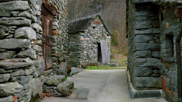 Fly-through drone shot of the stone houses in the village of Cavergno, located in the district of Vallemaggia, in the canton of Ticino in Switzerland.
