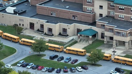 Large high school with line of buses for dismissal. Aerial establishing shot. - Powered by Adobe