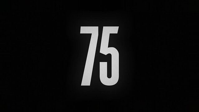 The number 75 smolders and burns on a black background, the number is on fire