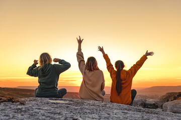 Three happy young girls are having fun and enjoys sunset from view point. Three silhouettes with...