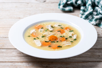 Chicken soup with vegetables on wooden table
