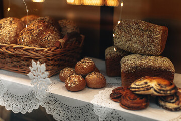 Soft multigrain bread and sweet buns in a wicker basket in a fresh baked goods store