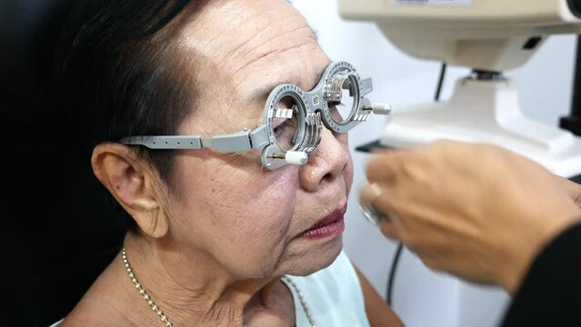 Using a trial frame, elderly is having her eyes checked manually in an optical shop in Bangkok, Thailand.