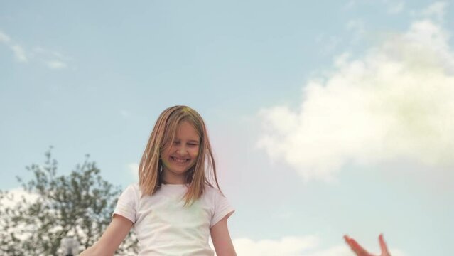 cute little girl playing with a holi powder throwing a colorful powder up, celebrating at Holi Festival