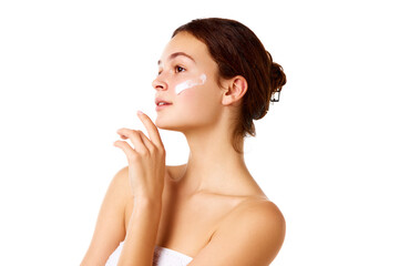 Side view image of young beautiful girl with bare shoulders standing with moisturizing cream on...