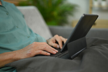 Fototapeta premium Cropped shot of middle age man working online or surfing internet on digital tablet