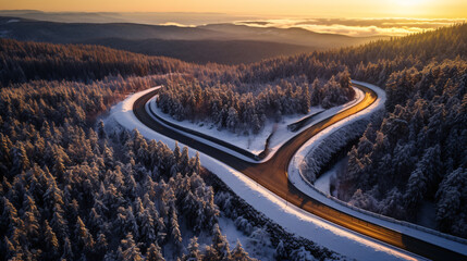 Curvy road by day from above, in the middle of a snow covered forest  - obrazy, fototapety, plakaty