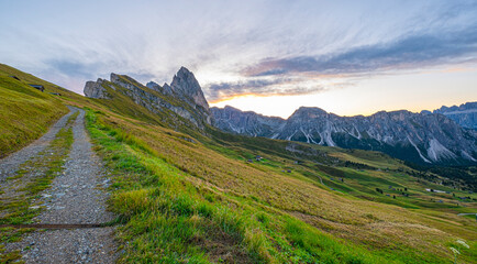 Dolomites' Seceda at sunrise, A golden spectacle graces the rugged landscape, casting warmth on iconic peaks, an enchanting start to the day in Italy's stunning mountains.