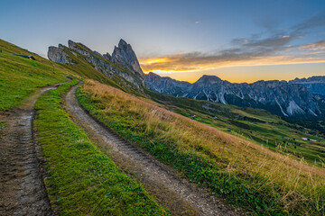 Golden sunrise at Seceda, Dolomites, Italy, A stunning spectacle bathes the rugged landscape and meadows in warm hues, creating a serene and radiant morning panorama.