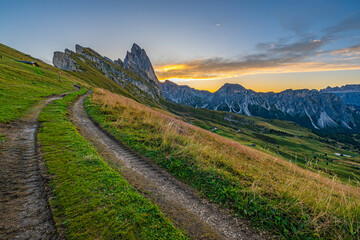 Fototapeta na wymiar Golden sunrise at Seceda, Dolomites, Italy, A stunning spectacle bathes the rugged landscape and meadows in warm hues, creating a serene and radiant morning panorama.