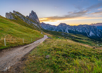 Golden sunrise at Seceda, Dolomites, Italy, A stunning spectacle bathes the rugged landscape and meadows in warm hues, creating a serene and radiant morning panorama