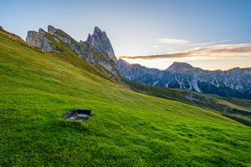 Seceda at sunrise, Golden hues paint the meadows, creating a breathtaking spectacle in the heart of the Dolomites, a serene and radiant morning scene.