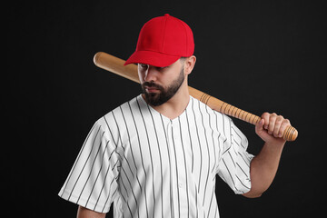 Man in stylish red baseball cap holding bat on black background