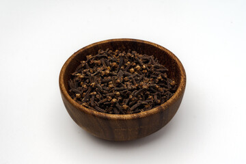 a wooden bowl full of cloves, isolated on a white background