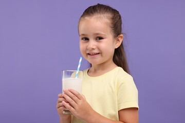 Cute girl with glass of fresh milk on violet background