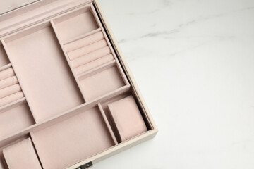 Empty beige jewelry box on white marble table, top view. Space for text