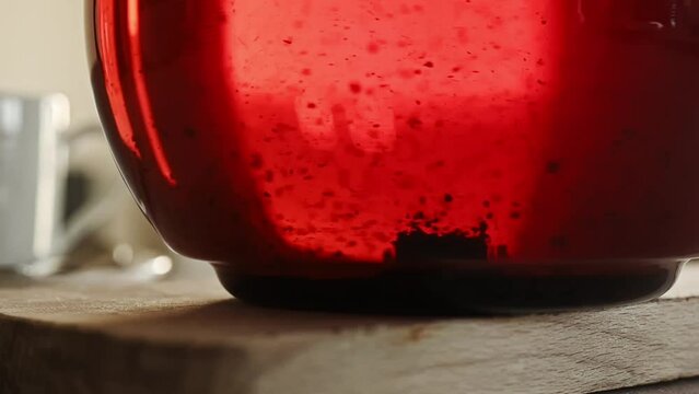 Black tea in transparent kettle during stiring closeup. Hot natural herbal beverage in kettle