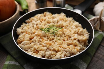 Fried ground meat in frying pan and microgreens on table, closeup