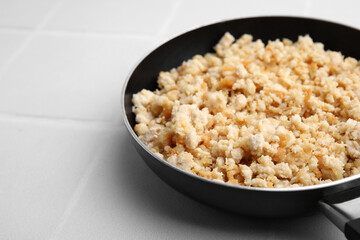 Fried ground meat in frying pan on white tiled table, closeup. Space for text