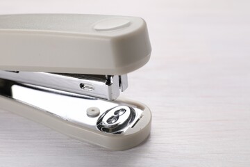 Beige stapler with staples on light wooden table, closeup. Space for text