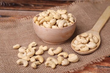 Tasty cashew nuts in bowl and spoon on table