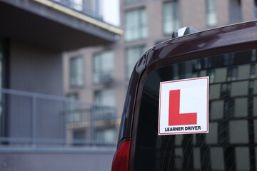 L-plate on car outdoors, closeup with space for text. Driving school