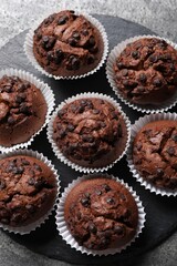 Tasty chocolate muffins on grey textured table, top view