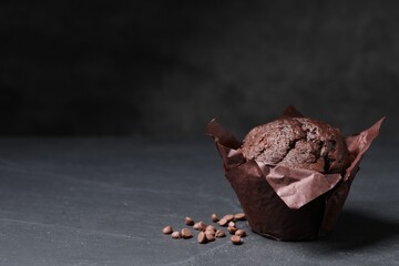 Tasty chocolate muffin on black textured table. Space for text