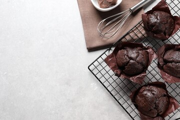 Tasty chocolate muffins and whisk on grey table, flat lay. Space for text