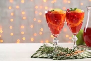 Christmas Sangria cocktail in glasses, cinnamon sticks and fir tree branch on white table against...