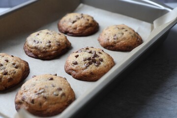 Baking pan with chocolate chip cookies on table, closeup