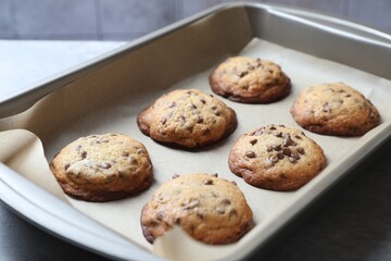 Baking pan with chocolate chip cookies on table, closeup