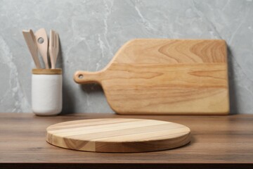 Wooden cutting boards and utensils on table near gray wall, closeup