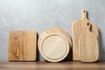 Different wooden cutting boards on table near gray wall