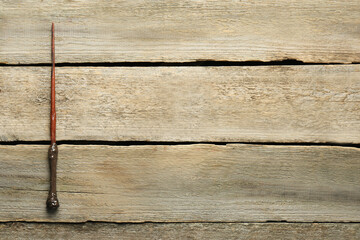 One old magic wand on wooden table, top view. Space for text