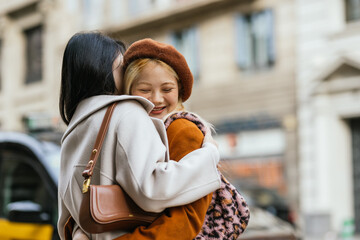 Women hugging each other while meeting on the street.