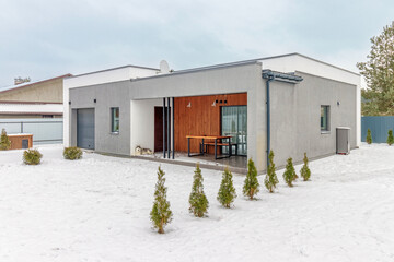 Modern one-storey house with a flat roof in winter - obrazy, fototapety, plakaty