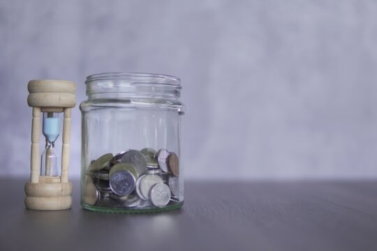 Closeup image of hourglass and coins with copy space for text. Financial concept.