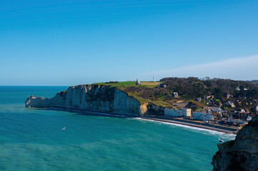 View of the town Étretat and chalk or limestone cliffs, Normandy, France. Seascape on a clear day.