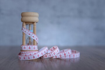 Closeup image of hourglass and measuring tape. Copy space for text. Diet and weight loss concept.