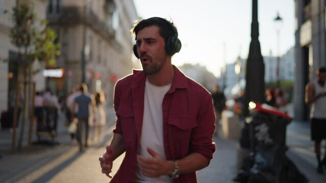 Exuberant man singing along to music with joy on a bustling city street, emoting with hands outstretched. A candid moment capturing urban energy and passion for life