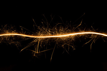 Christmas festive abstract background with burning curved line of sparkler on black background,...
