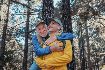 Happy family couple of grandfather and young grandson hugging while hiking in the mountains...